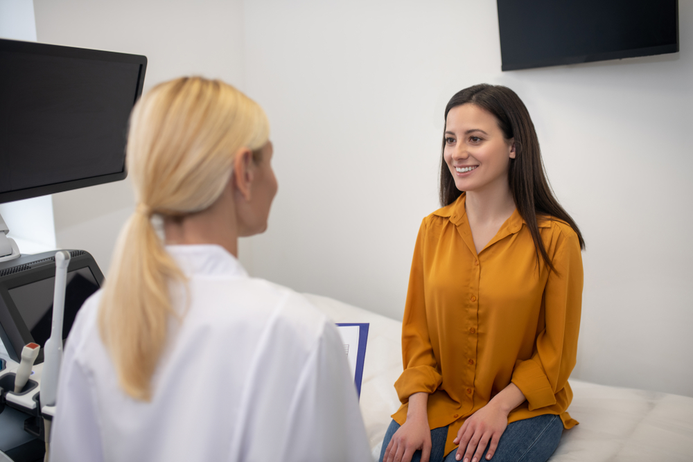 Good news. Young female patient feeling happy and smiling while talking to her doctor