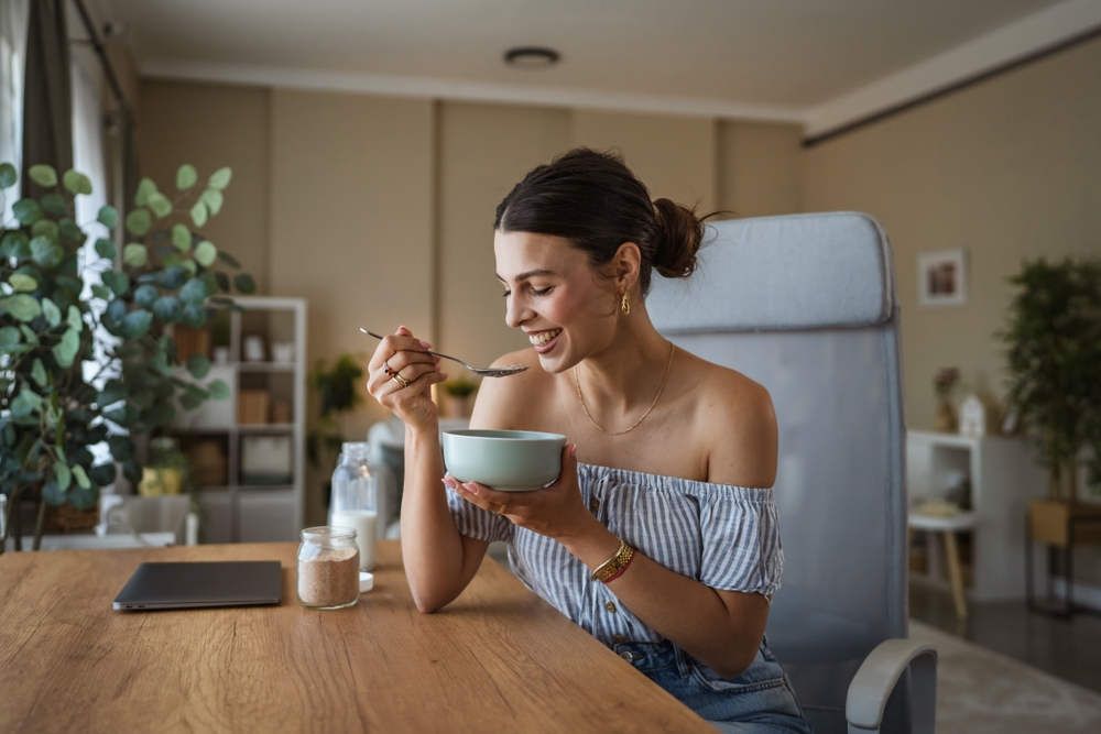 Portrait of adult caucasian woman sit at table in the living room eat healthy breakfast in the living room